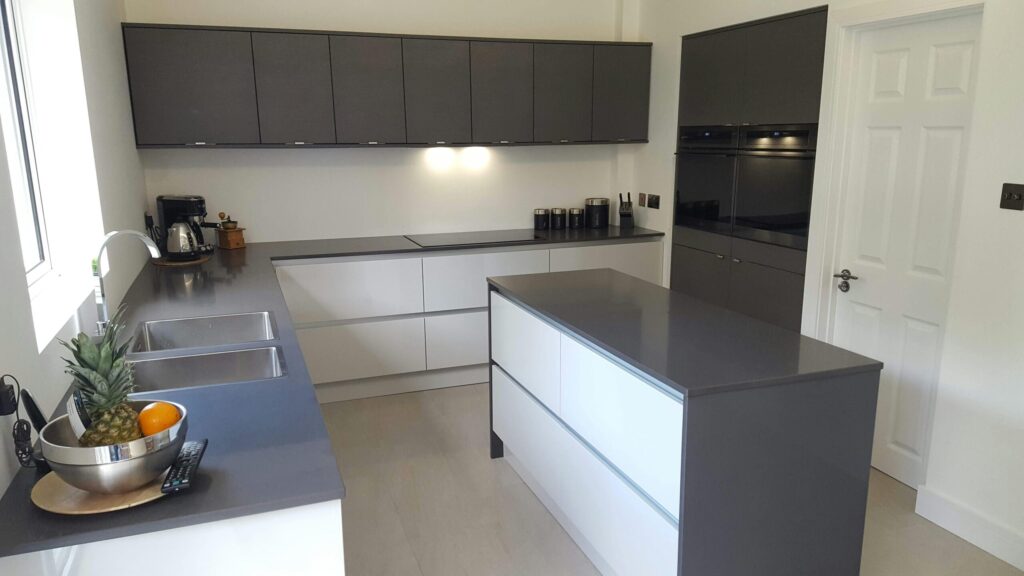 Sleek modern kitchen with dark cabinets, island, and elegant lighting.