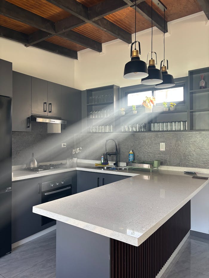 A contemporary kitchen bathed in sunlight showcasing elegant cabinetry and a spacious countertop.